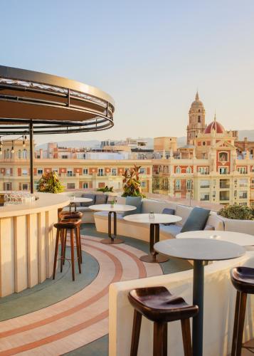 a rooftop bar with tables and chairs and a city at Only YOU Hotel Málaga in Málaga