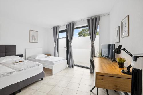 a bedroom with two beds and a desk and a tv at ANDRISS - Travel & Work - 5 BR - Kitchen - Parking in Kaiserslautern