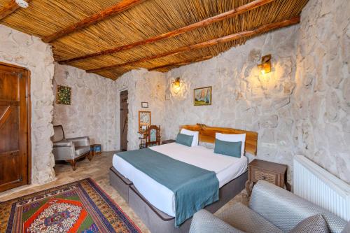 a bedroom with a bed and two chairs in a room at Cappadocia Nar Cave House & Swimming Pool in Nevşehir