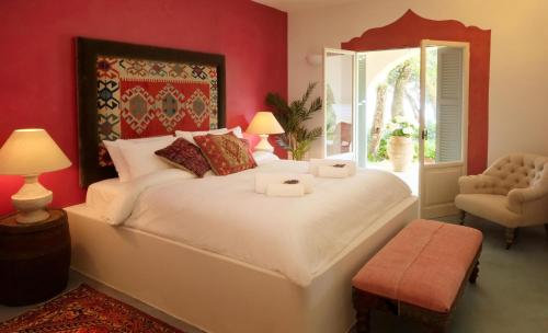 a bedroom with a large white bed and a chair at Purple Apricot Hotel in Vlachopoulátika
