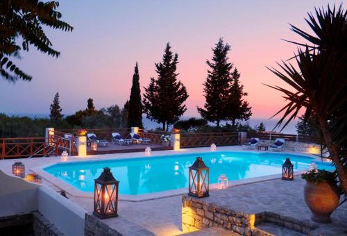 a swimming pool with lights in a backyard at dusk at Purple Apricot Hotel in Vlachopoulátika