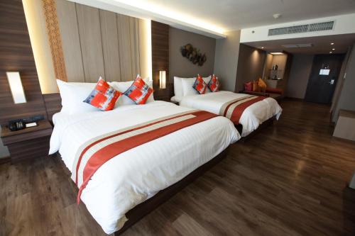 two beds in a hotel room with white and red pillows at Arte Hotel - SHA Extra Plus in Bangkok