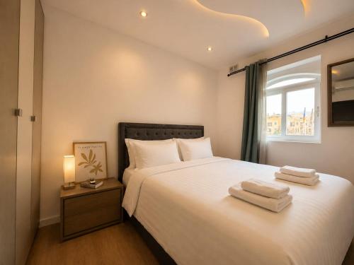 a bedroom with a white bed with towels on it at Spacious Townhouse - Private Jacuzzi -Swieqi in Is-Swieqi