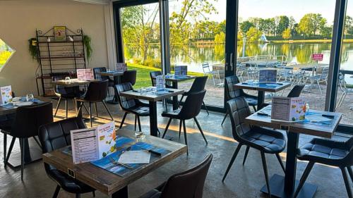 een kamer met tafels en stoelen en een groot raam bij Base de loisirs du Colvert in Bonzée-en-Woëvre