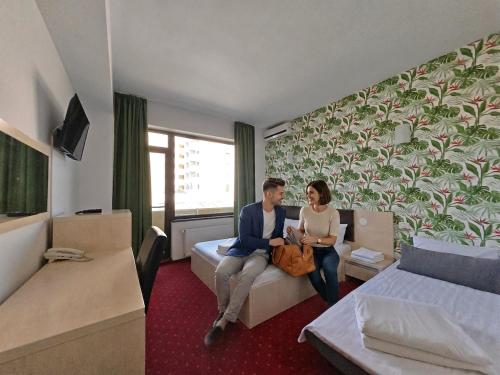 a man and woman sitting on a couch in a hotel room at Alma by iVAVev Is'us in Mamaia