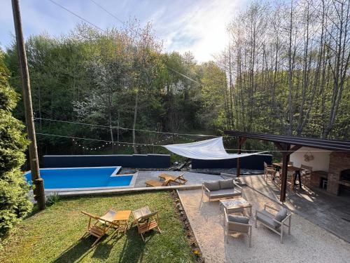 a backyard with a table and chairs and a tent at Maca - vikendica sa bazenom in Ahatovići