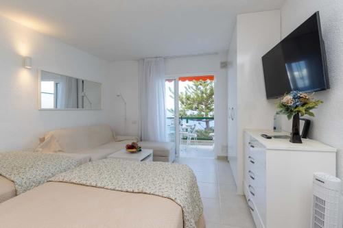 a white room with a bed and a couch and a tv at Ocean View 3 in Los Cristianos