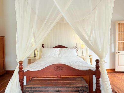 a bedroom with a canopy bed with a trunk at Curious Prince in Prince Albert