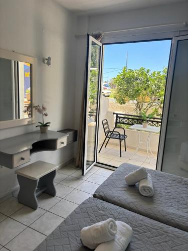 a bedroom with two beds and a desk and a balcony at Kostas Apartments in Stalís