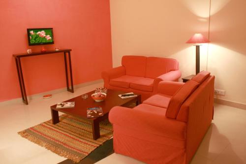 a living room with red chairs and a table at Sterling Living Space - Residency Road in Bangalore