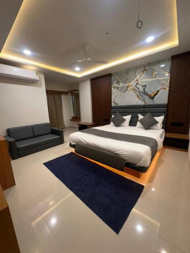 a bedroom with a king sized bed and a couch at Hotel Peacock Anand in Anand