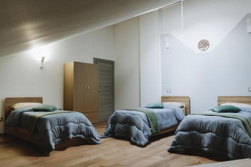 two beds in a room with white walls and wooden floors at Aura Residence in San Biagio