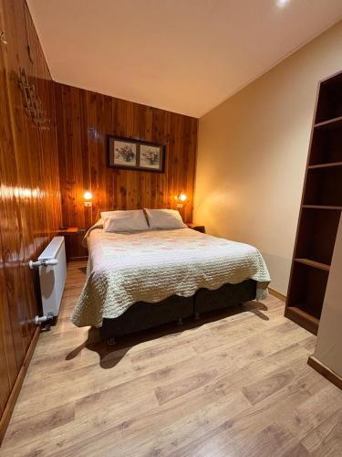 a bedroom with a large bed with wooden walls at Hostal Graciela in Pucón
