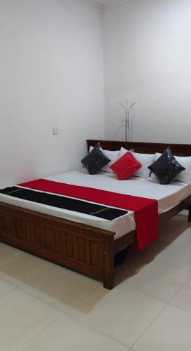 a large bed with red and black pillows on it at Elite moon hotel in Kallady