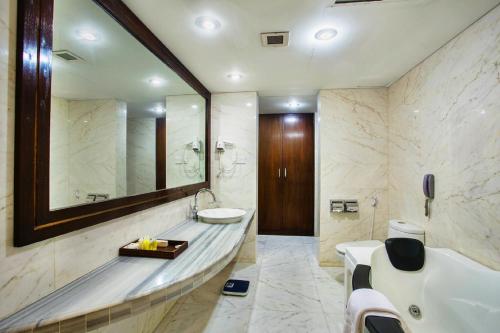 a bathroom with a tub and a sink and a mirror at Rose View Hotel Sylhet in Sylhet