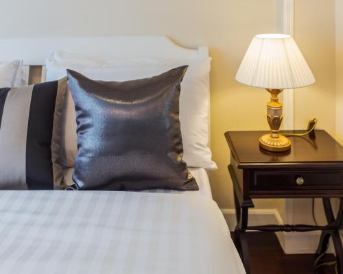 a bed with a black pillow and a lamp on a night stand at The Lek Aree in Bangkok