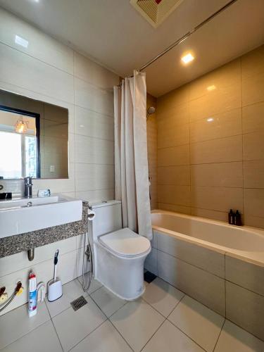 a bathroom with a toilet and a sink and a tub at Luxe Gold Mactan in Mactan