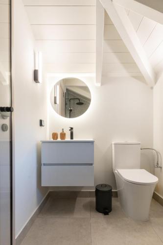 a white bathroom with a toilet and a mirror at Olea Stone Villa in Pylos