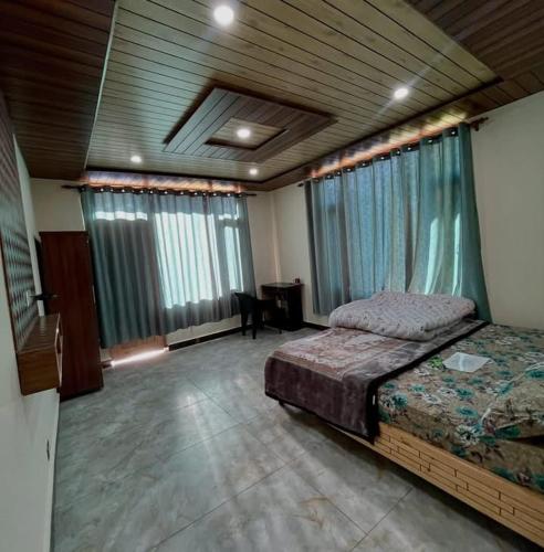 a bedroom with a bed and a desk and windows at Nimat Nivas By Fuwa Homestay in Vashisht