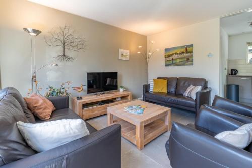 a living room with two couches and a tv at Landhuis Tempelierweg 23 in Den Burg