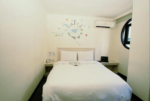 a white bed in a small room with a white bedspread at Century Hotel in Kaohsiung