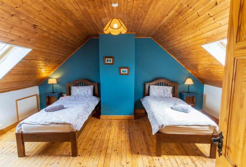 two beds in a room with blue walls and wooden floors at Perewinkle Cottage - Portmagee in Lateeve