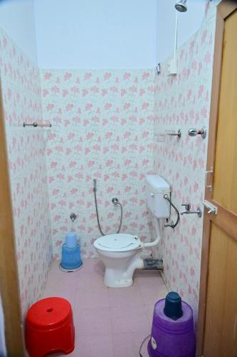 a bathroom with a toilet with pink and white wallpaper at SUN SHINE RESORT in Neil Island