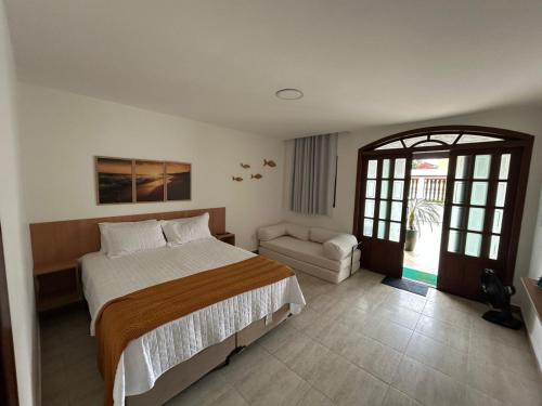 a bedroom with a bed and a couch in it at Casa da Dinda102 in Rio das Ostras