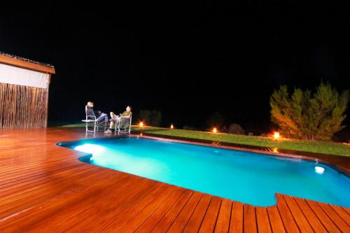 dos personas sentadas en sillas junto a una piscina por la noche en Agama Tented Camp, en Garies
