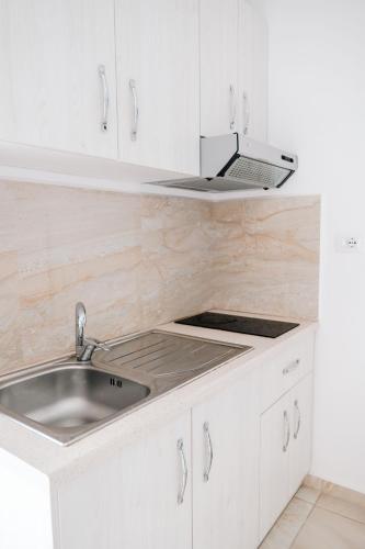 a white kitchen with a sink and a stove at Vila Finnley in Ksamil