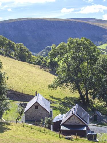 two old barns in a field with a tree at Cwm Clyd - Carthouse in Rhayader