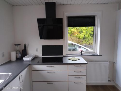 a white kitchen with a sink and a window at Venos Home 2 in Lemvig