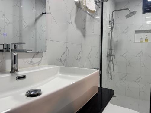 a white bathroom with a sink and a shower at Rindhali Thoddoo in Thoddoo
