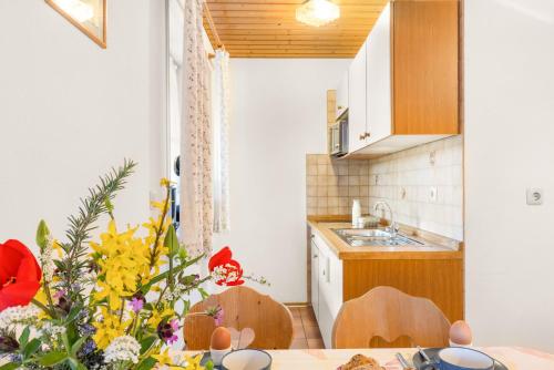 a kitchen with a table with a vase of flowers at Mayerbauer in Piding