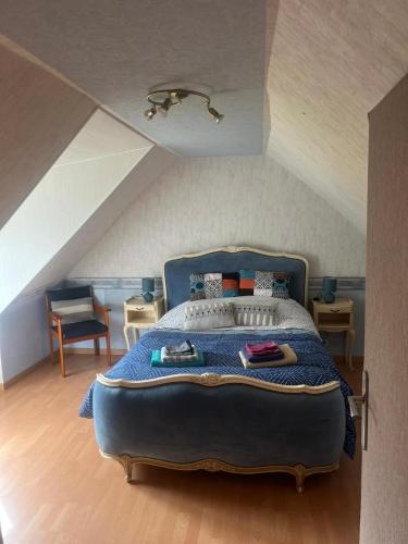 a bedroom with a blue bed in an attic at Gîte de L'embarcadère in Moustéru