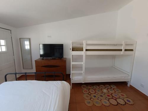 a bedroom with a bunk bed and a television at Casinha do Rui in Sines