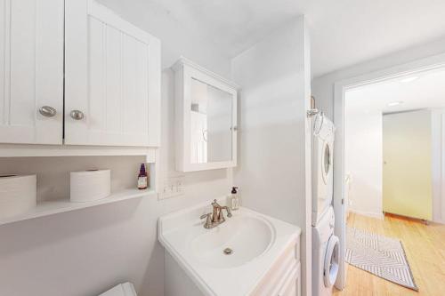 a white bathroom with a sink and a mirror at Yellow Door Cottage in Meredith