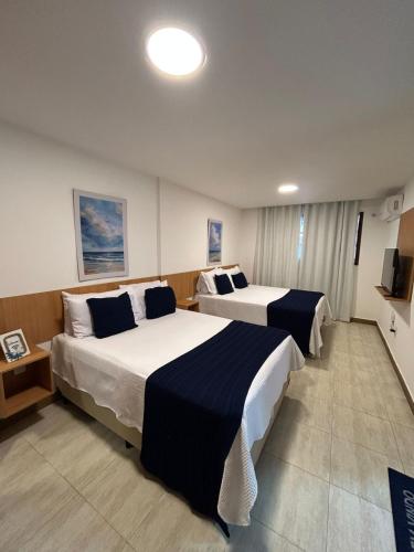 a hotel room with two beds and a television at Casa da Dinda 104 in Rio das Ostras