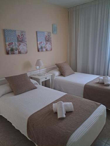 two beds in a hotel room with towels on them at Apartamentos Cala Llonga in Cala Llonga