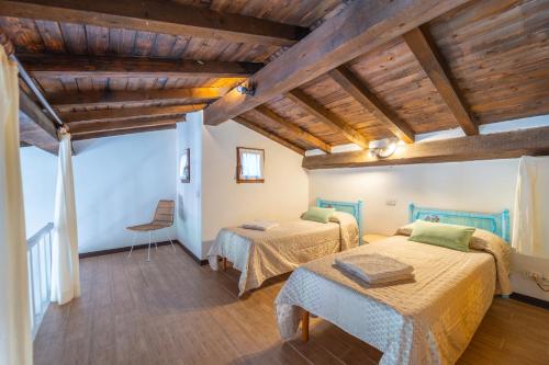 two beds in a room with wooden ceilings at Mury by DomusAway in Porto Istana