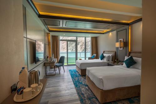 a hotel room with two beds and a television at Pearl Continental Attabad Lake, Hunza in Hunza Valley