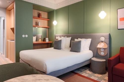 a bedroom with a large white bed with green walls at Hotel Aparthotel AMMI Nice Lafayette in Nice