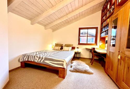 a bedroom with a bed and a desk and a window at AlpenLodge Chiemsee in Nußdorf