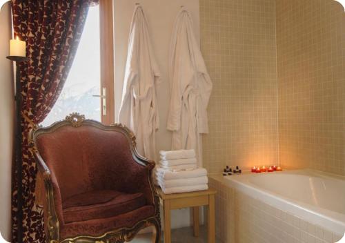 a bathroom with a tub and a chair next to a bath tub at Chalet Broski - Spacious Chalet with Hot Tub, Sauna & BBQ in Planvillard