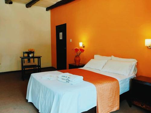 a bedroom with a large bed with an orange wall at Casona del Inca Cajamarca in Cajamarca