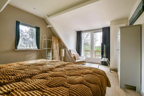 a bedroom with a bed and a chair and windows at The Rietvink Residence in Wervershoof