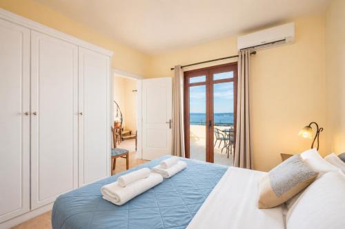 a bedroom with a blue bed with a view of the ocean at Villa Aphrodite in Plaka
