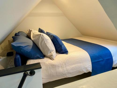 a bed with blue and white pillows in a attic at Hawks Hideaway in Warminster