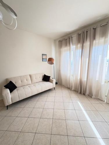 a white living room with a couch and some windows at Sydney Apartment in Frosinone
