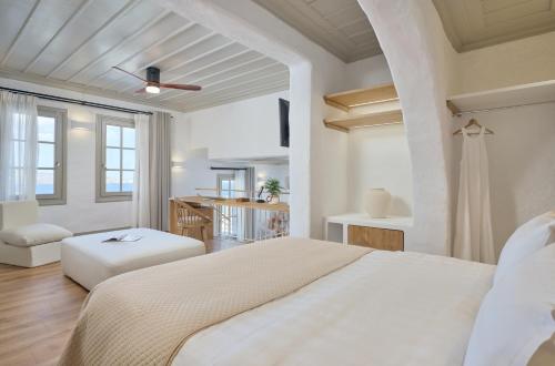 a white bedroom with a bed and a table at Tholaria Boutique Hotel in Astypalaia